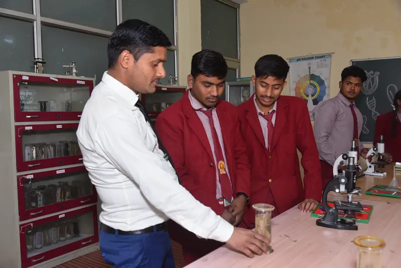 A biology teacher with students beside the microscopes