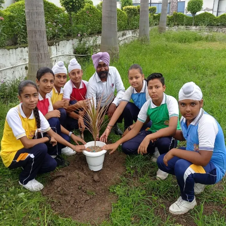 Students and a teacher planting a sapling