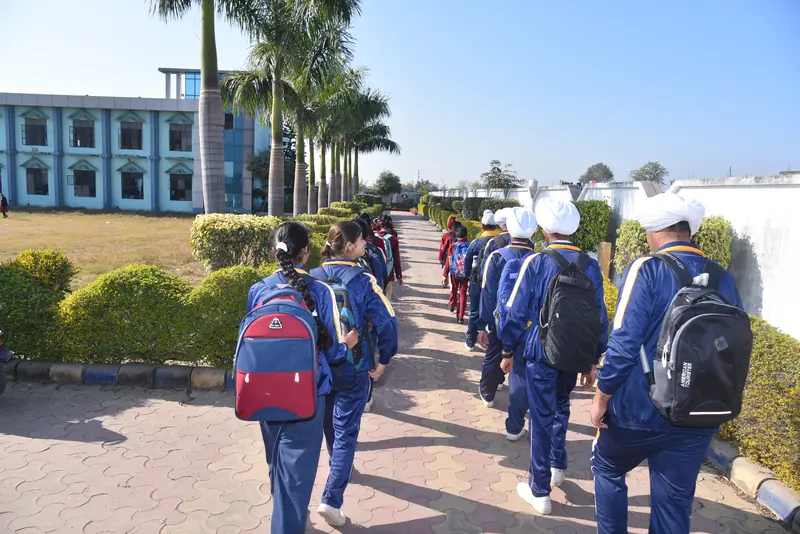 Students with backpacks walking down the palm-lined path